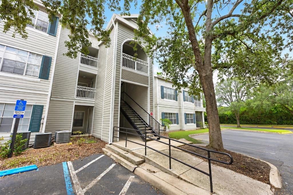 An exterior view of a multi-story apartment building with a wheelchair ramp and stairs — 5118 CITY STREET UNIT 514, ORLANDO, FL