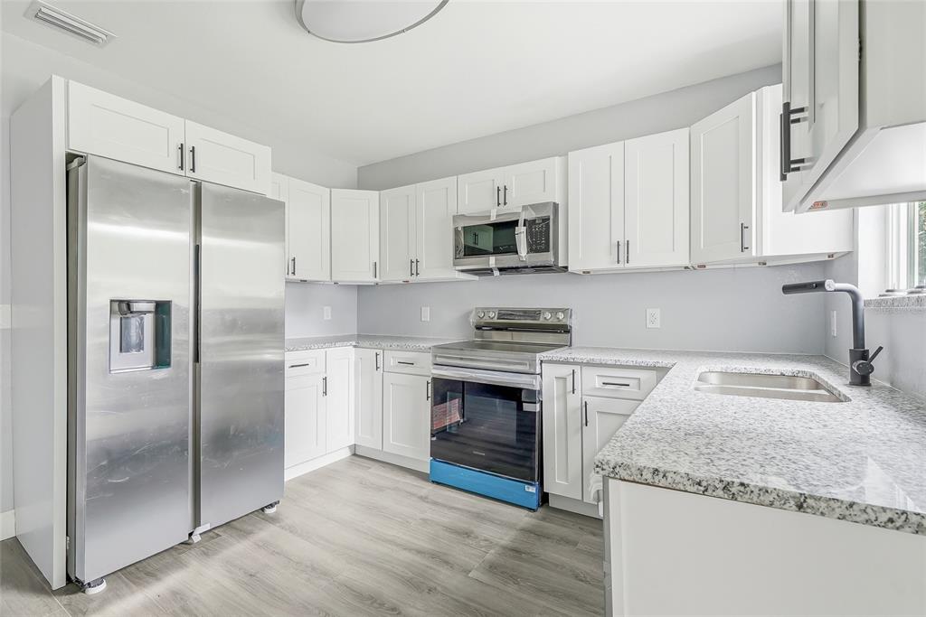 A bright room with light blue walls, wood-look flooring, a ceiling fan, and three windows — 8500 N BOULEVARD, TAMPA, FL