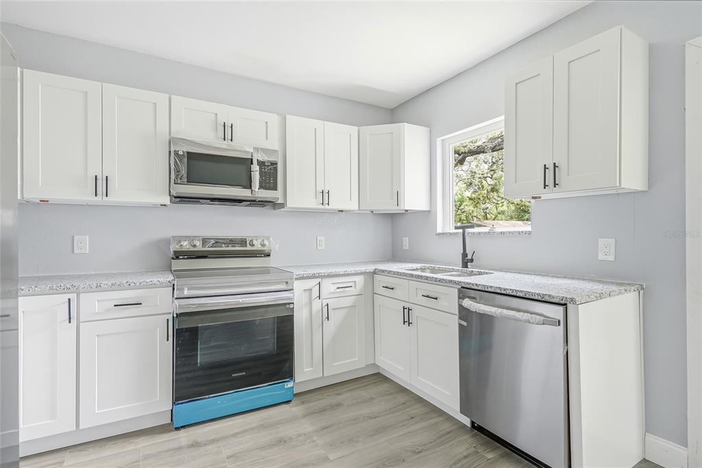 A bright room features light blue walls, gray wood-look flooring, and a ceiling fan — 8500 N BOULEVARD, TAMPA, FL