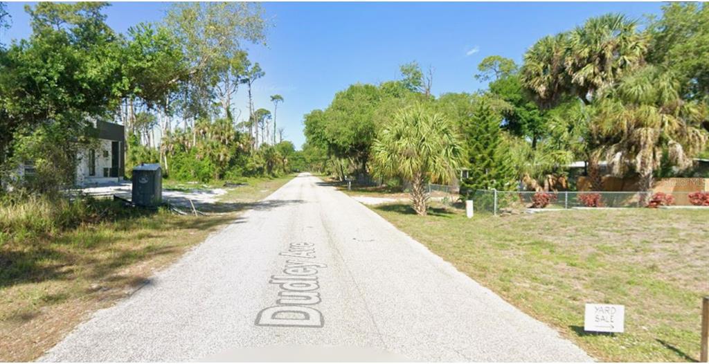 A gravel road lined with trees and vegetation leads into a residential neighborhood — 17469 & 17477 DUDLEY AVENUE, PORT CHARLOTTE, FL