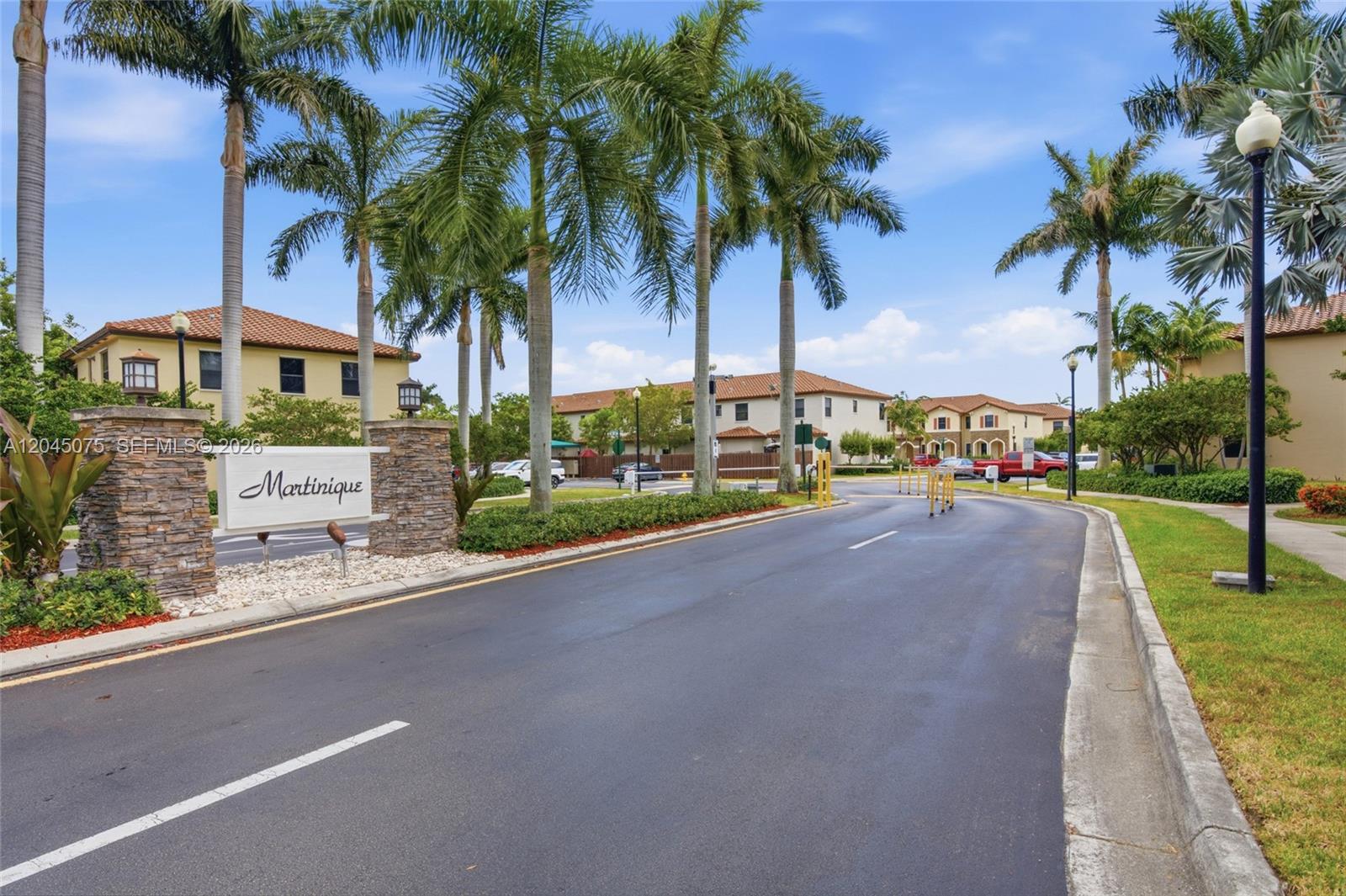 A paved entrance road leads to a residential community with palm trees and stone pillars — 540 SE 32nd Ave, Homestead FL 33033, HOMESTEAD, FL