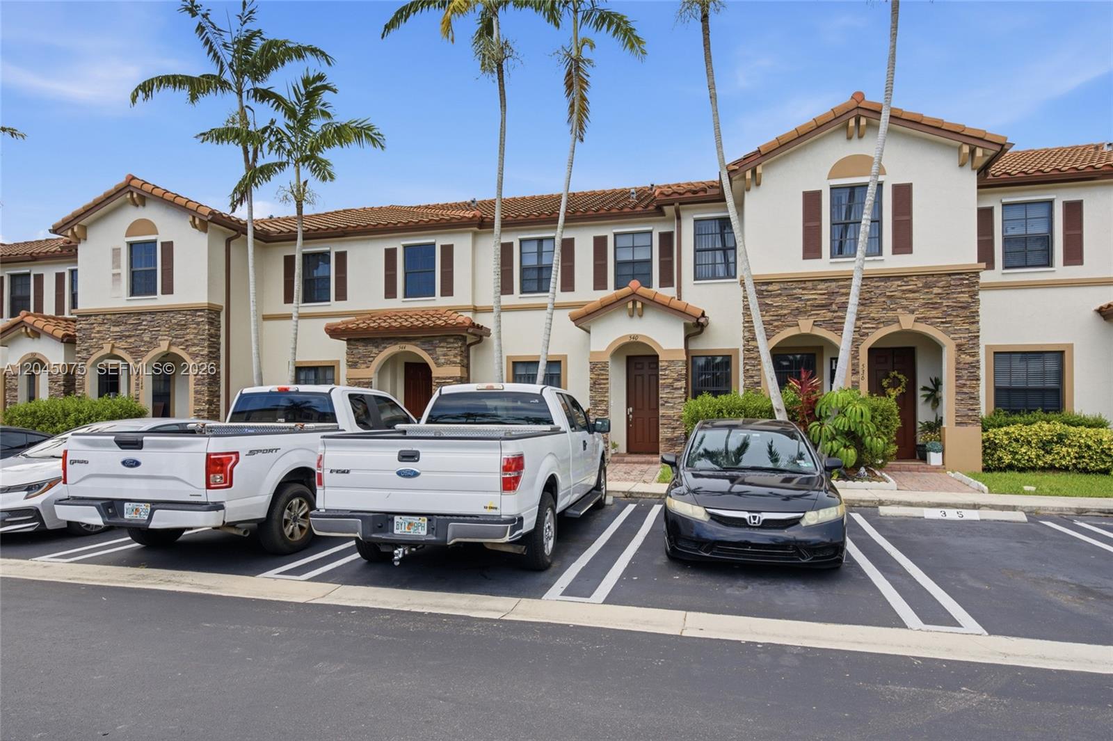 A row of two-story townhouses with stone accents and parking spaces in front — 540 SE 32nd Ave, Homestead FL 33033, HOMESTEAD, FL