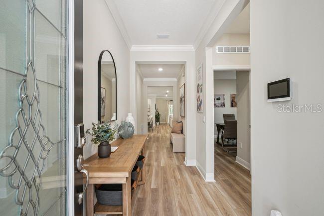 A bright entryway features a wooden console table, arched mirror, and light wood-look flooring — 13077 MEINERT AVENUE, BROOKSVILLE, FL