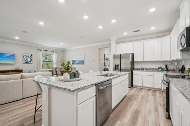 A kitchen with white cabinets, granite countertops, and stainless steel appliances opens to a living area — 13077 MEINERT AVENUE, BROOKSVILLE, FL