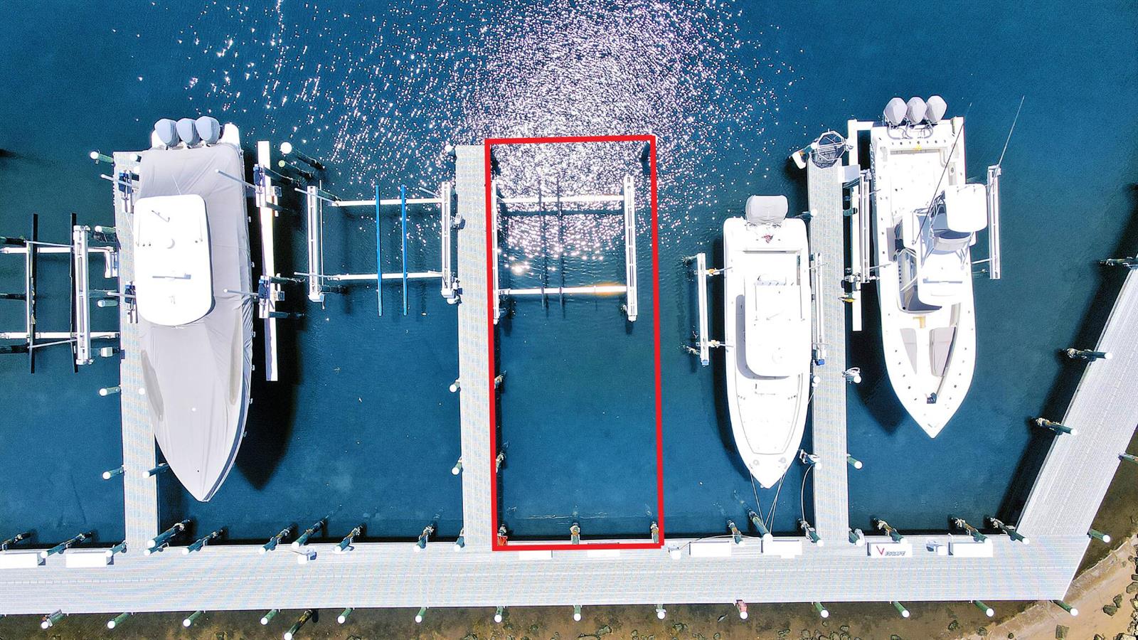 An aerial view shows a vacant boat slip with a lift between two occupied slips — 543 Bay Colony Drive N Slip 8, Juno Beach FL 33408, JUNO BEACH, FL