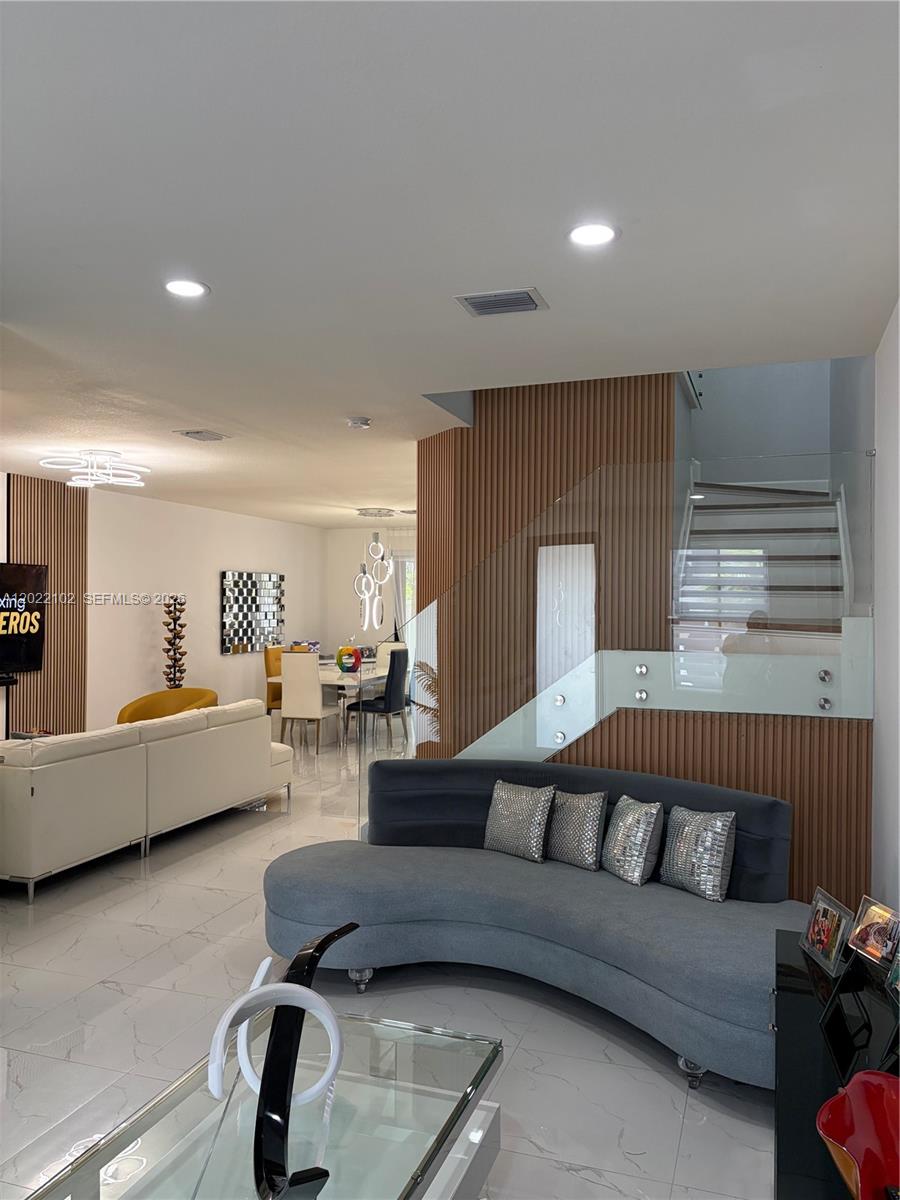 A living room features a curved gray sofa, white leather sectional, and wood-slatted wall accents — 3409 W 92nd Pl, Hialeah FL 33018, HIALEAH, FL