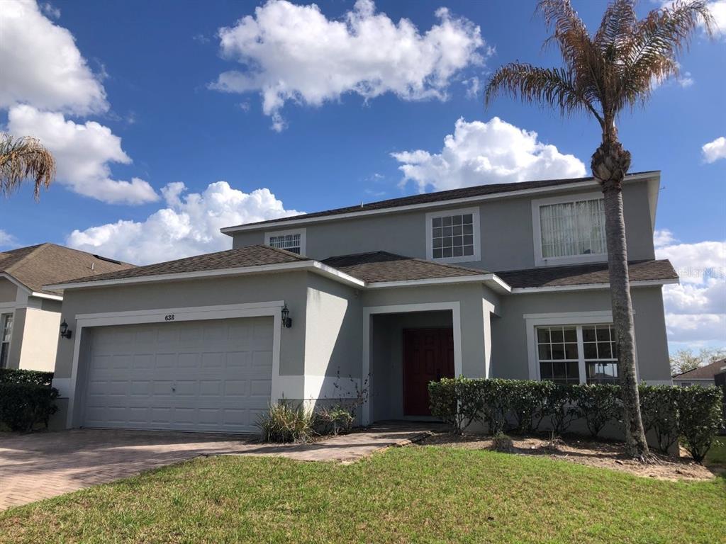 A two-story house with a gray exterior, a two-car garage, and a palm tree — 638 KENSINGTON DRIVE, DAVENPORT, FL