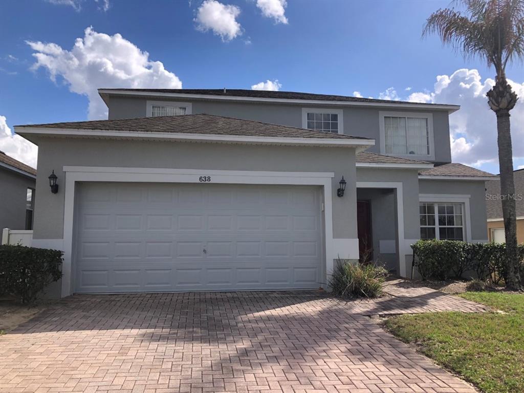 A two-story house with a gray exterior, a two-car garage, and a brick paver driveway — 638 KENSINGTON DRIVE, DAVENPORT, FL