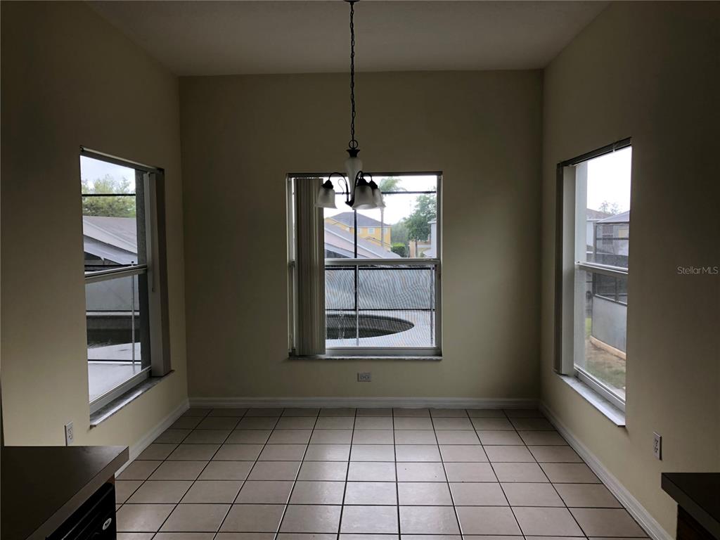 A dining area with tile flooring, a central chandelier, and three windows overlooking a pool — 638 KENSINGTON DRIVE, DAVENPORT, FL