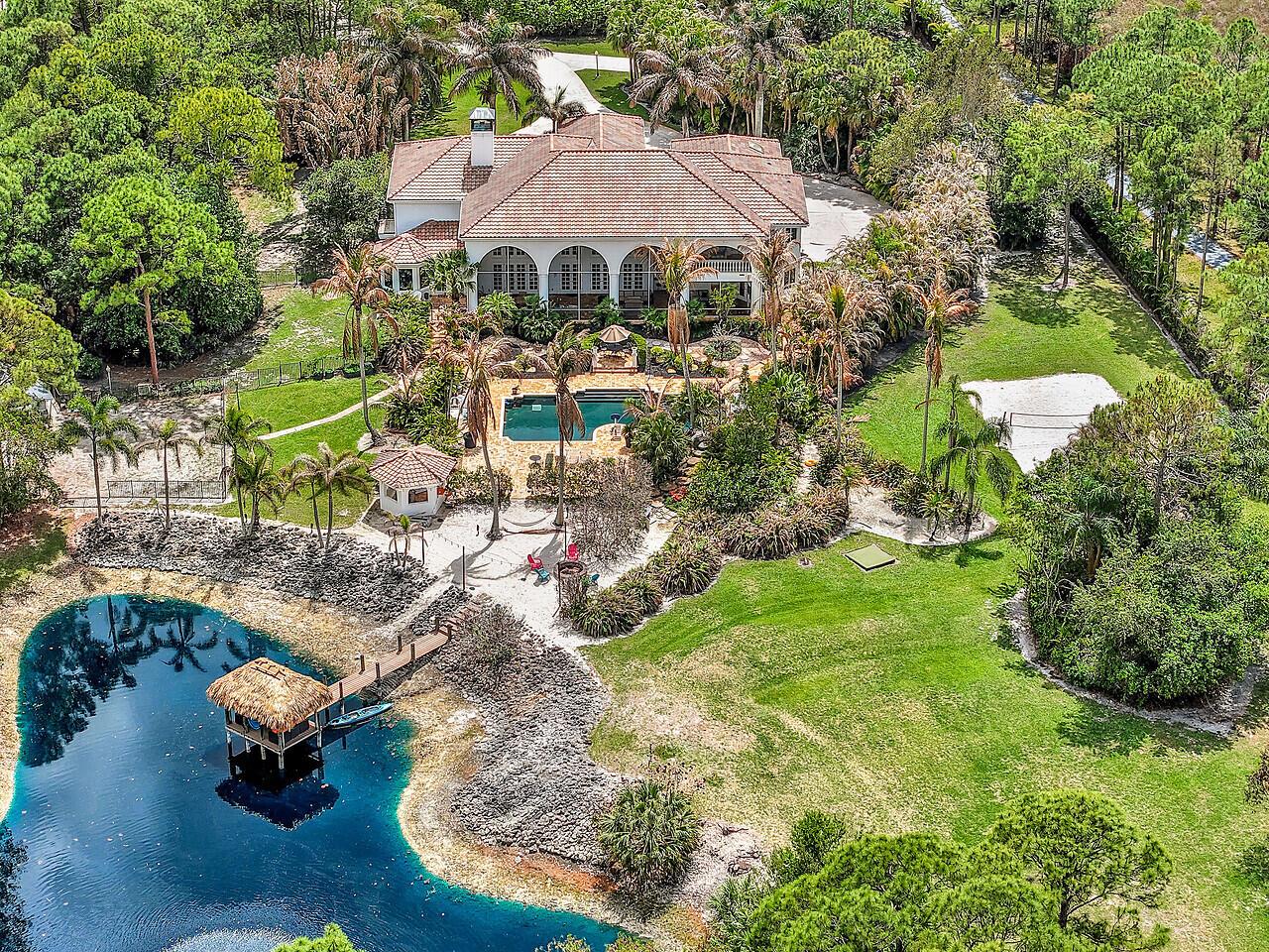 An aerial view of a large house with a pool, dock, and pond — 2584 SE Ranch Acres Circle, Jupiter FL 33478, JUPITER, FL