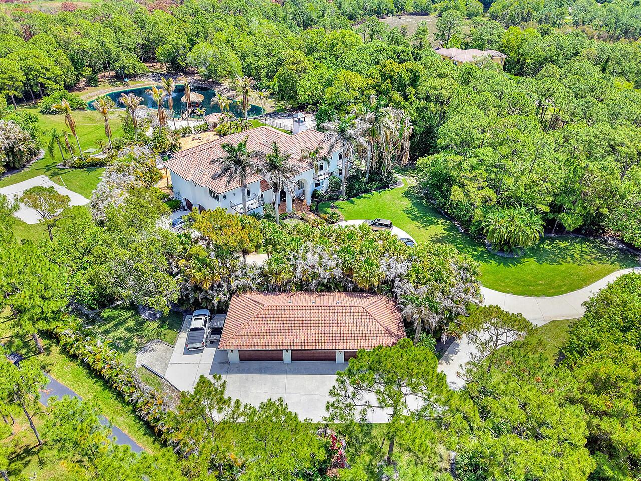 An aerial view shows a large house with a tile roof, pool, and detached garage — 2584 SE Ranch Acres Circle, Jupiter FL 33478, JUPITER, FL