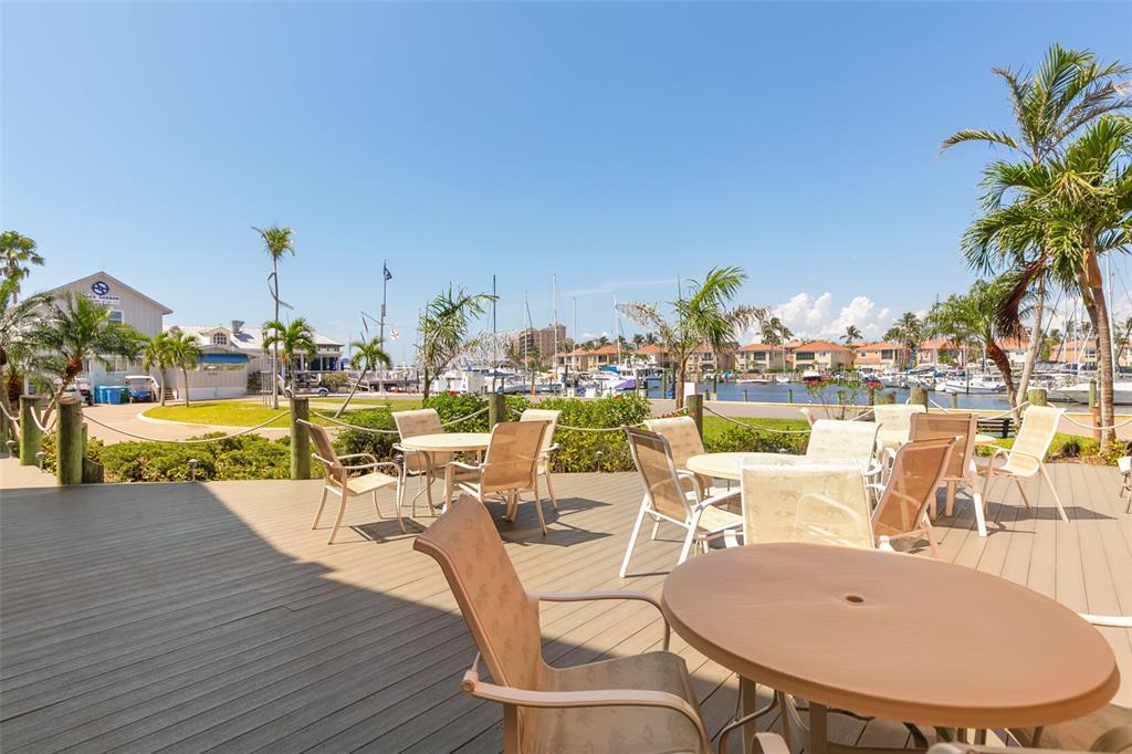 An outdoor wooden deck features several dining tables and chairs overlooking a boat marina — 3160 MATECUMBE KEY ROAD UNIT 233, PUNTA GORDA, FL