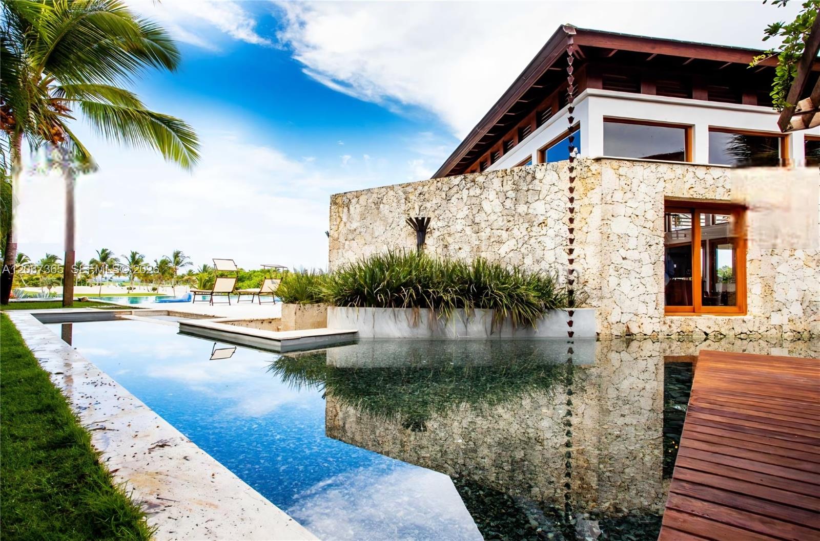 A modern house with a stone exterior wall overlooks a rectangular swimming pool and patio — 0 Las Palma, FL, FL