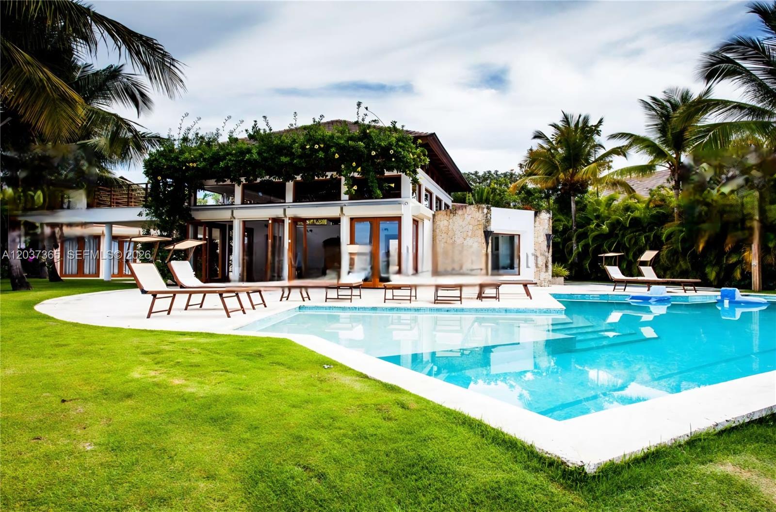 A modern house with a pool, patio, and palm trees under a cloudy sky — 0 Las Palma, FL, FL