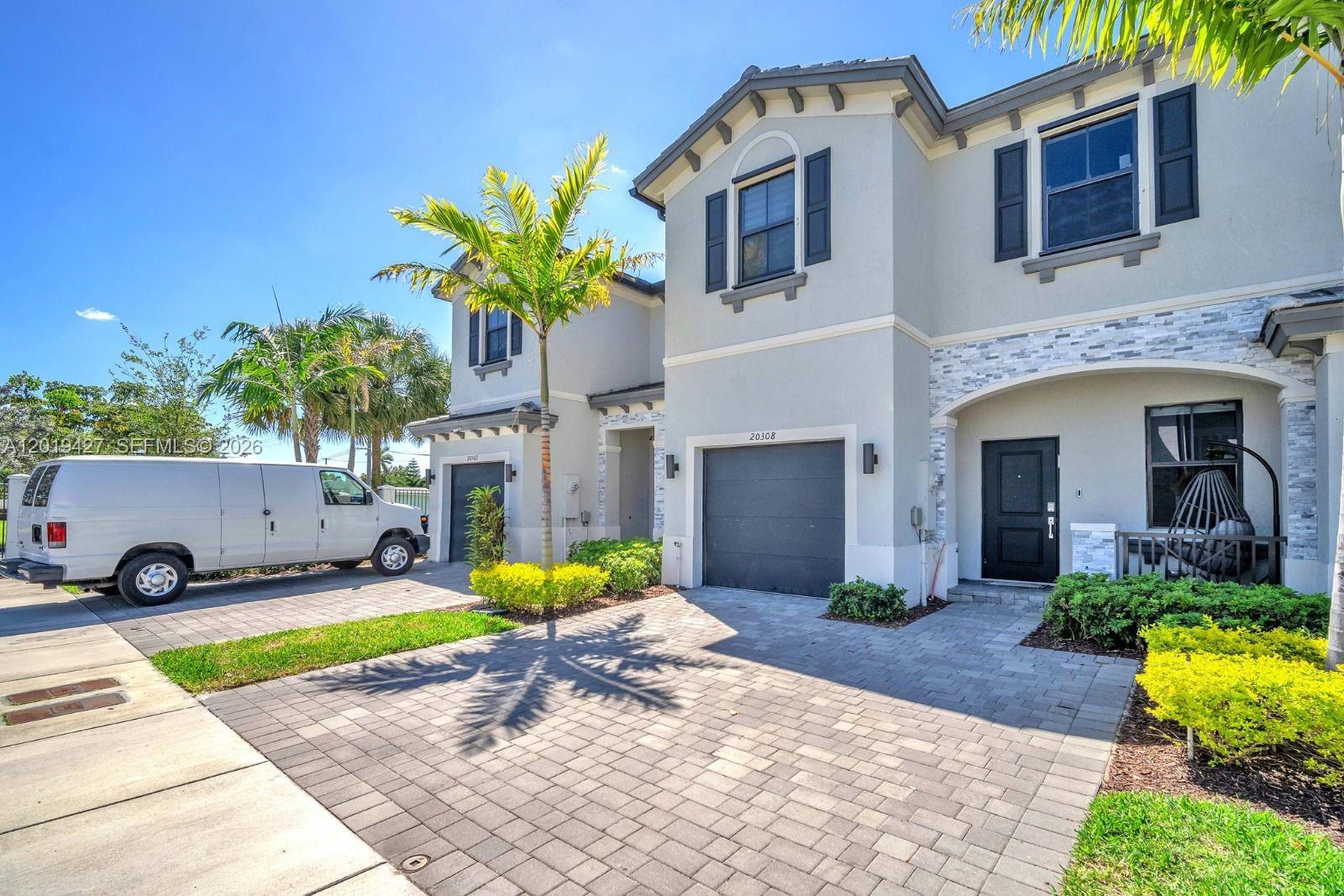 A two-story residential building with a paved driveway, a garage, and a white van parked outside — 20308 NW 6th Pl, Miami Gardens FL 33169, MIAMI GARDENS, FL