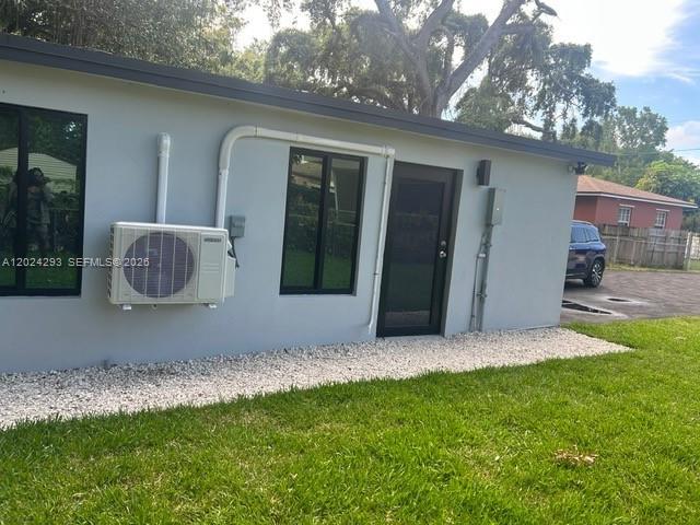 The exterior of a gray building features a window, a door, and an AC unit — MIAMI, FL