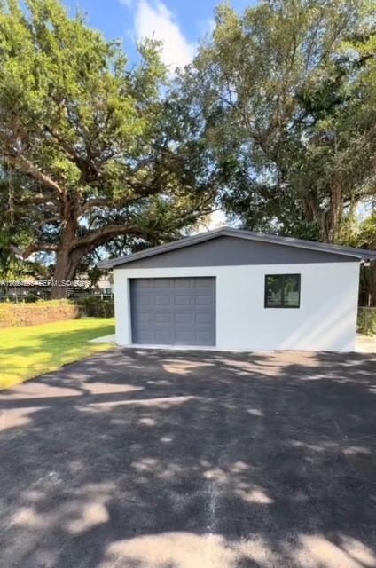 A detached garage with a gray door and white walls sits on an asphalt driveway — MIAMI, FL
