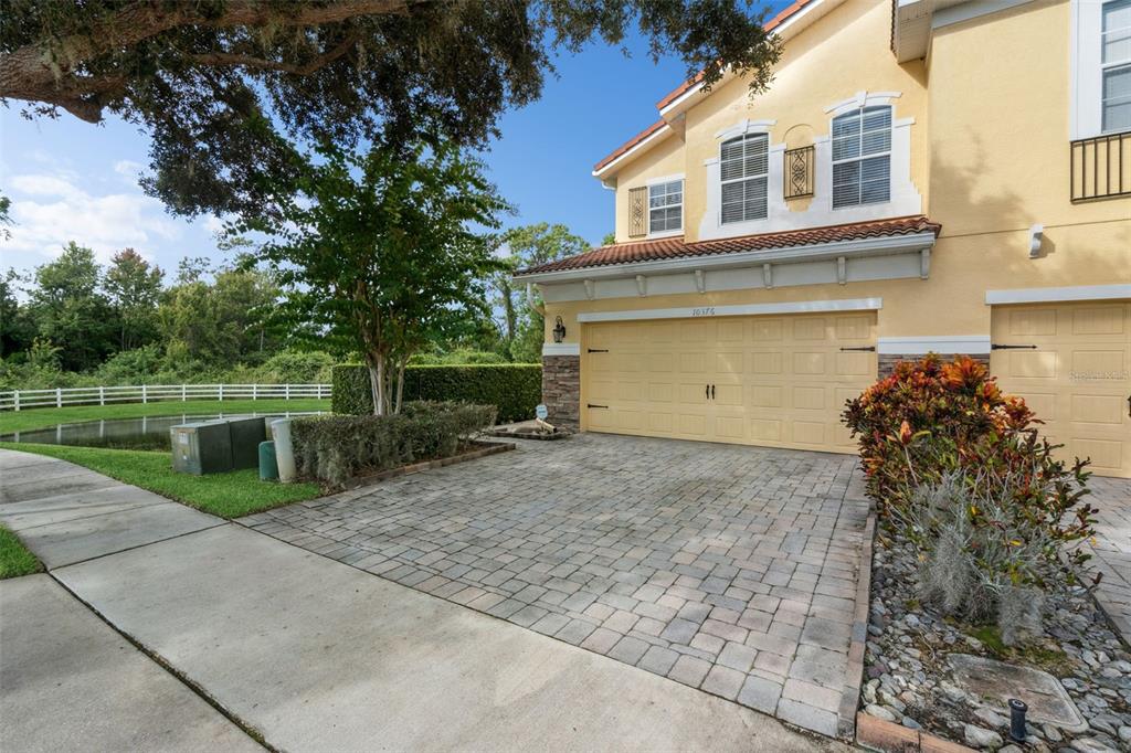 A two-story yellow house features a paved driveway, a two-car garage, and landscaping — 10376 FALLSGROVE STREET, ORLANDO, FL