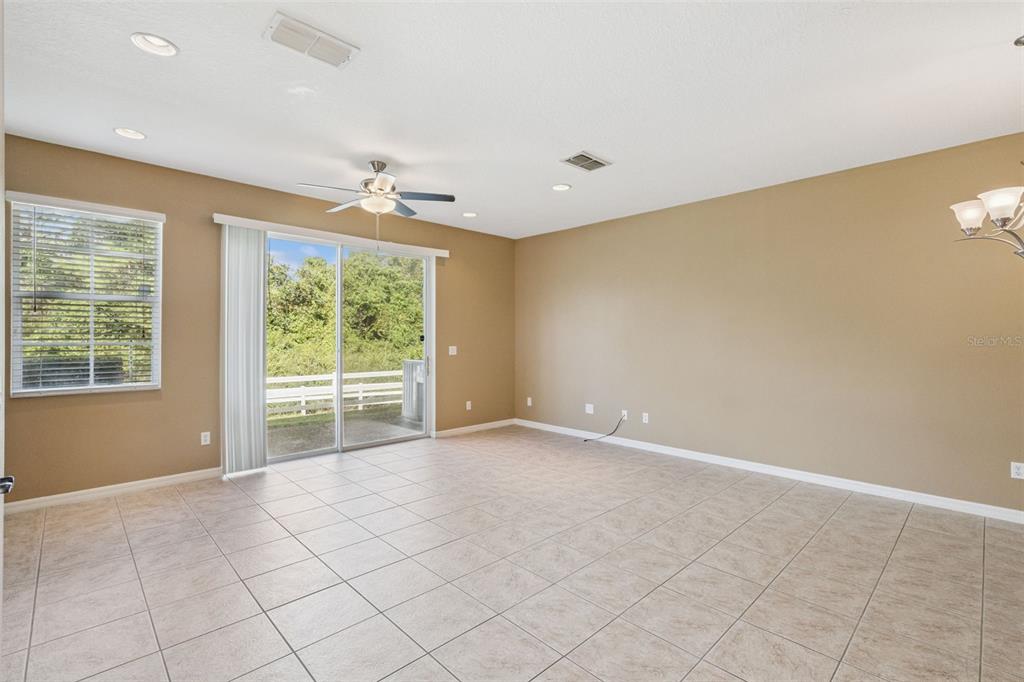 A spacious living area features beige walls, tile flooring, a ceiling fan, and sliding doors — 10376 FALLSGROVE STREET, ORLANDO, FL