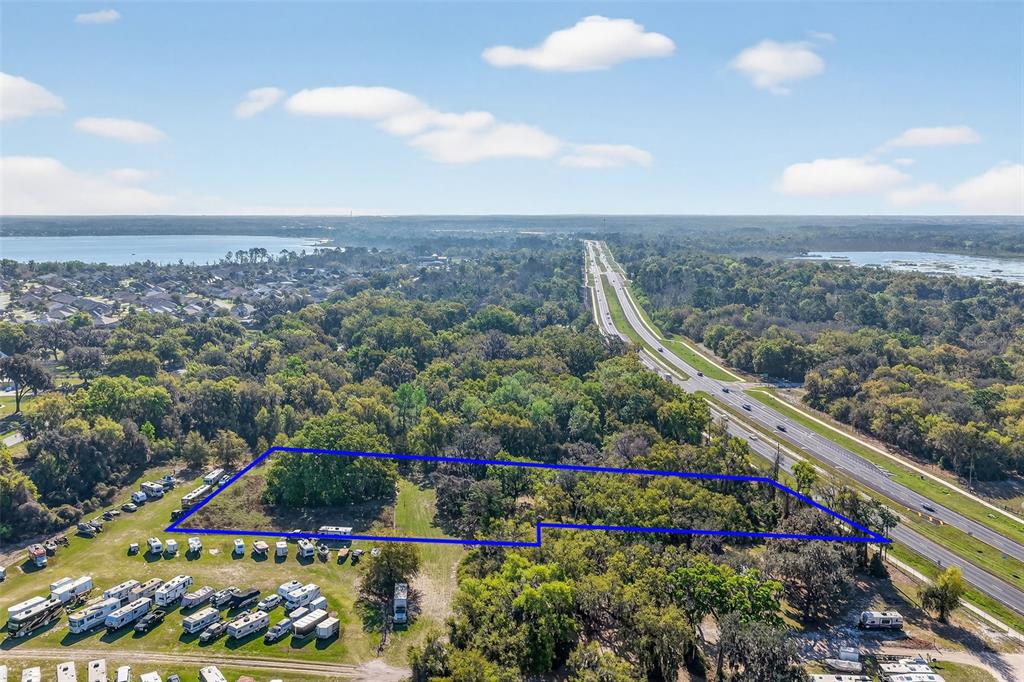 An aerial view shows a rectangular plot of land outlined in blue near a highway — 5932 E STATE ROAD 44, WILDWOOD, FL