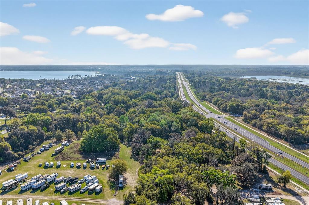 An aerial view shows a highway running through a wooded area near a lake and RVs — 5932 E STATE ROAD 44, WILDWOOD, FL