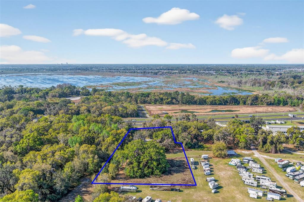 An aerial view shows a wooded lot outlined in blue next to an RV park — 5932 E STATE ROAD 44, WILDWOOD, FL