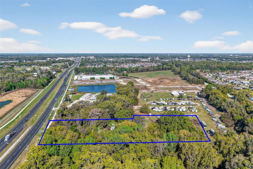 An aerial view shows a rectangular plot of land outlined in blue near a highway — 5932 E STATE ROAD 44, WILDWOOD, FL