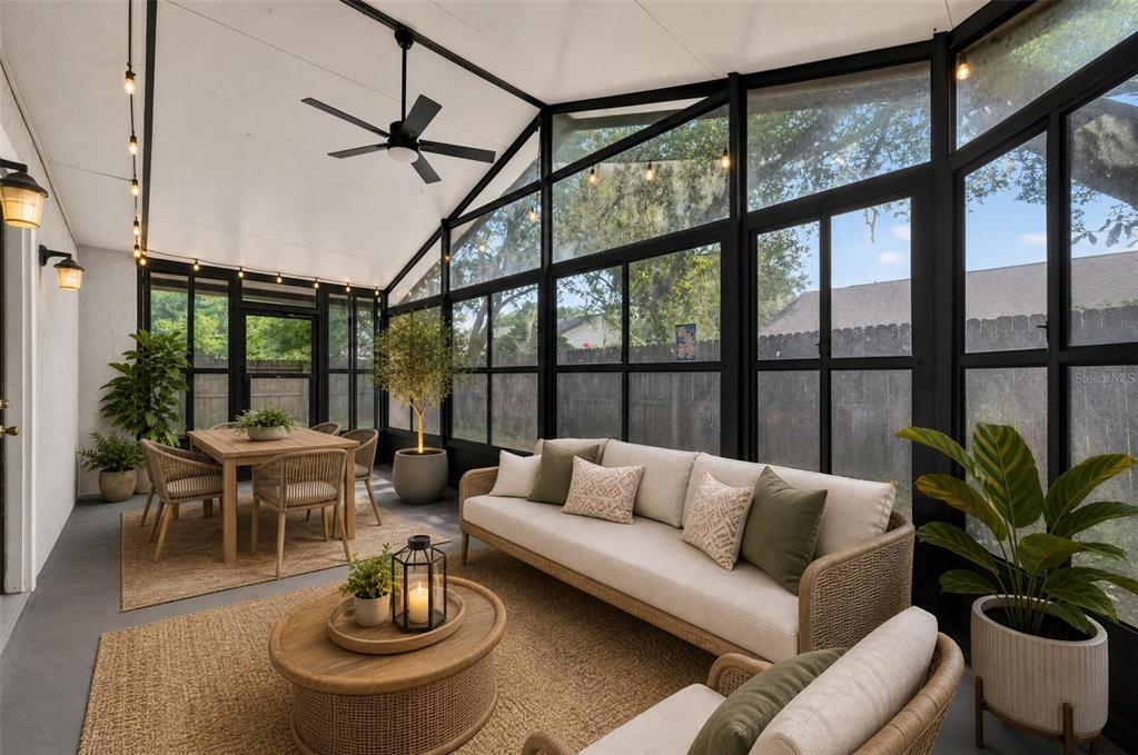 A screened-in porch features a dining area, a seating area, and large black-framed windows — 117 SHADY OAK LANE, OVIEDO, FL