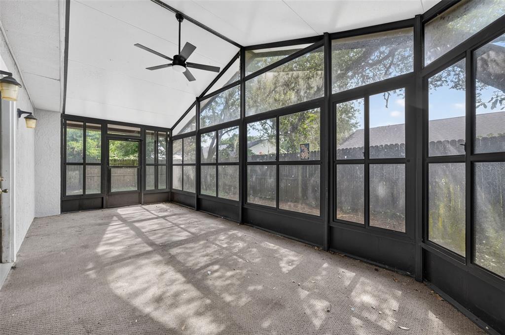 A screened-in porch with a ceiling fan, carpeted flooring, and large windows overlooking a yard — 117 SHADY OAK LANE, OVIEDO, FL