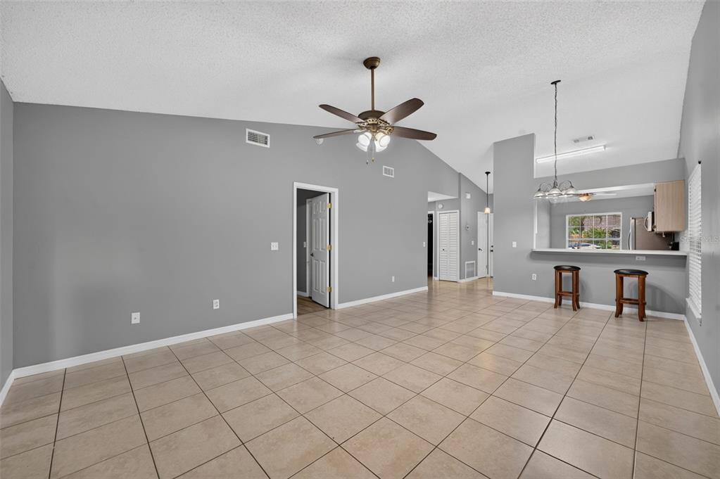 An open-concept living area features gray walls, tile flooring, a vaulted ceiling, and a breakfast bar — 117 SHADY OAK LANE, OVIEDO, FL