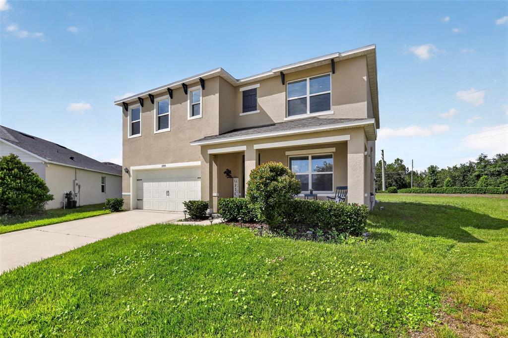A covered front porch features a dark blue door with a wreath and two rocking chairs — 3995 MEKONG COURT, ST CLOUD, FL