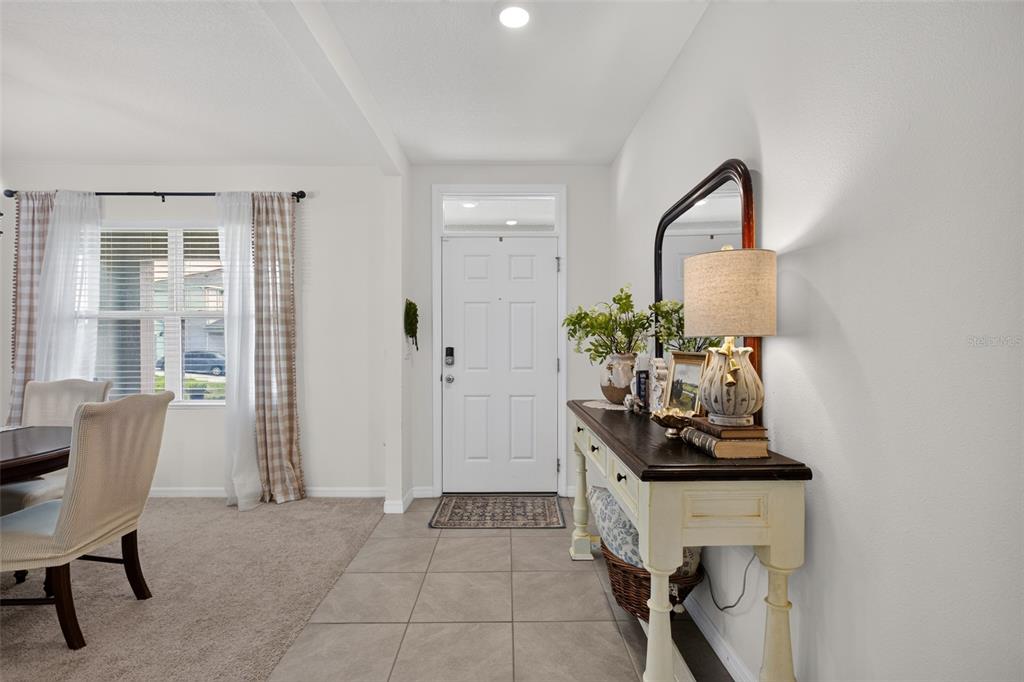 A dining room features a round table, upholstered chairs, a chandelier, and a large window — 3995 MEKONG COURT, ST CLOUD, FL