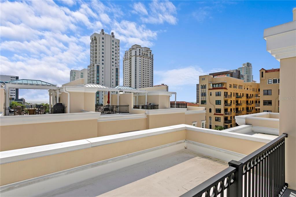 A rooftop terrace with a black metal railing overlooks neighboring buildings and high-rise towers — 412 REGENT LANE N, ST PETERSBURG, FL