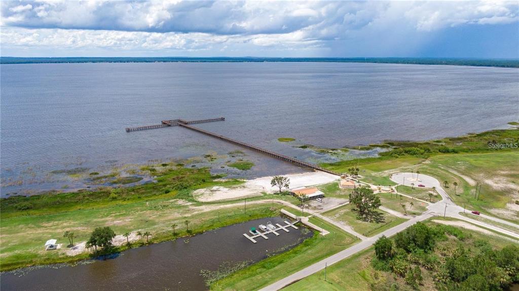 An aerial view shows a long wooden pier extending into a large lake near a pond — 0 OLEANDER DRIVE, INDIAN LAKE ESTATES, FL