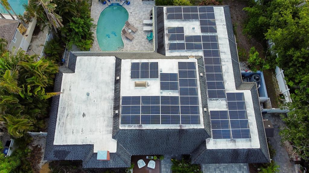 An aerial view of a house roof featuring multiple solar panel arrays and a swimming pool — 4925 PRIMROSE PATH, SARASOTA, FL