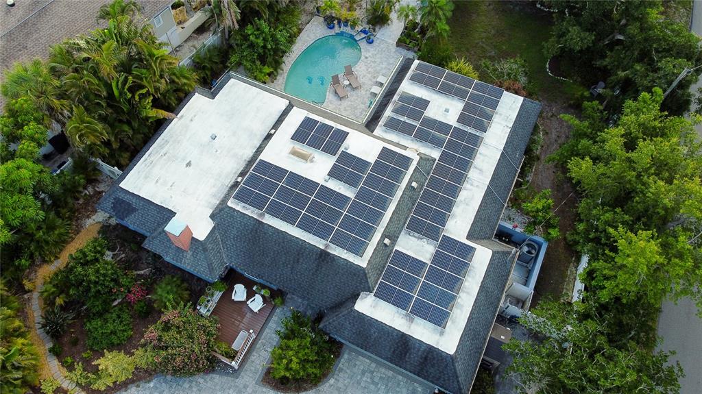 An aerial view shows a house with a flat roof featuring multiple solar panel arrays — 4925 PRIMROSE PATH, SARASOTA, FL