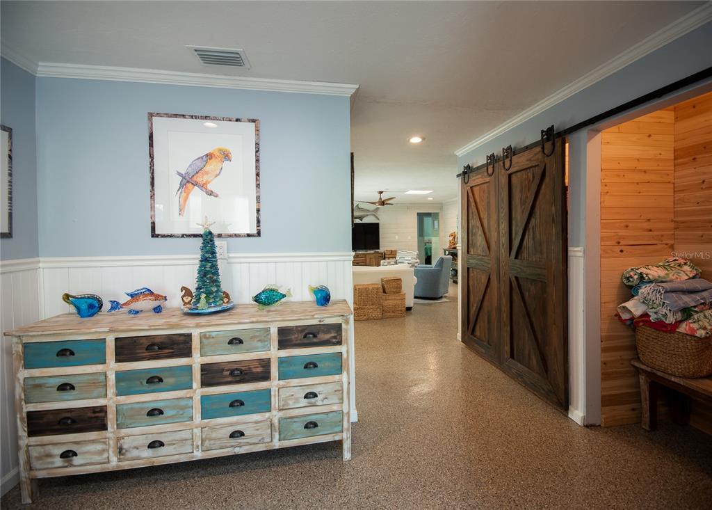 A hallway features a distressed wooden dresser, sliding barn doors, and a wood-paneled storage area — 4925 PRIMROSE PATH, SARASOTA, FL