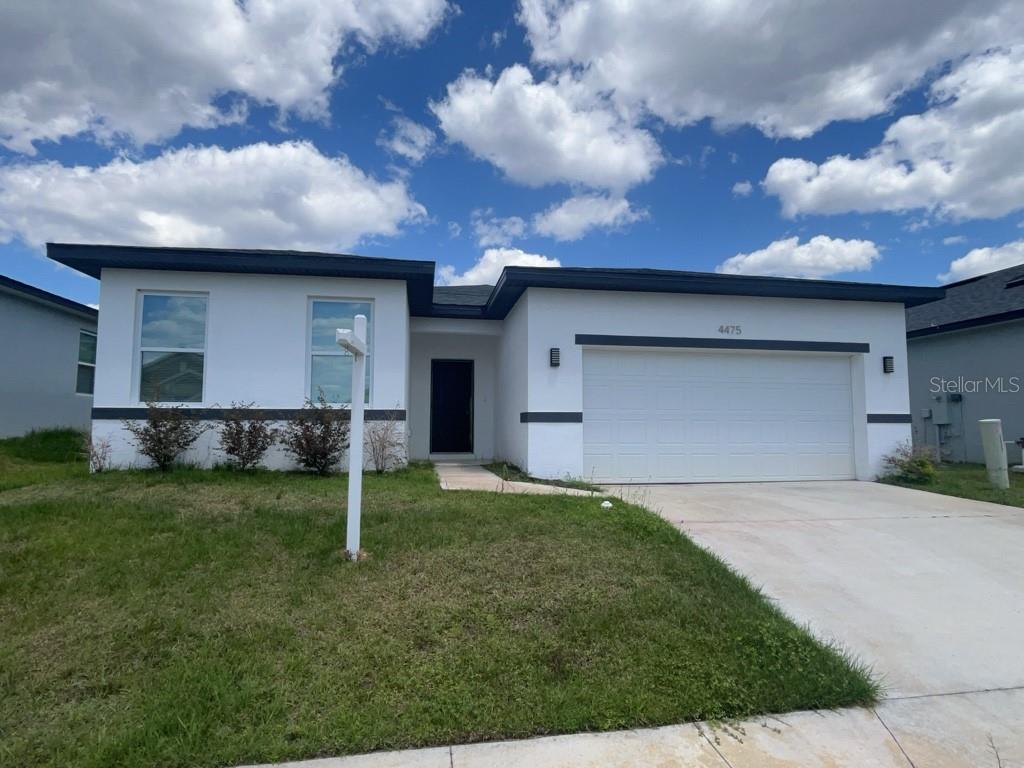 A single-story house with white stucco walls, dark trim, and a two-car garage — 4475 NW 1ST TERRACE, OCALA, FL