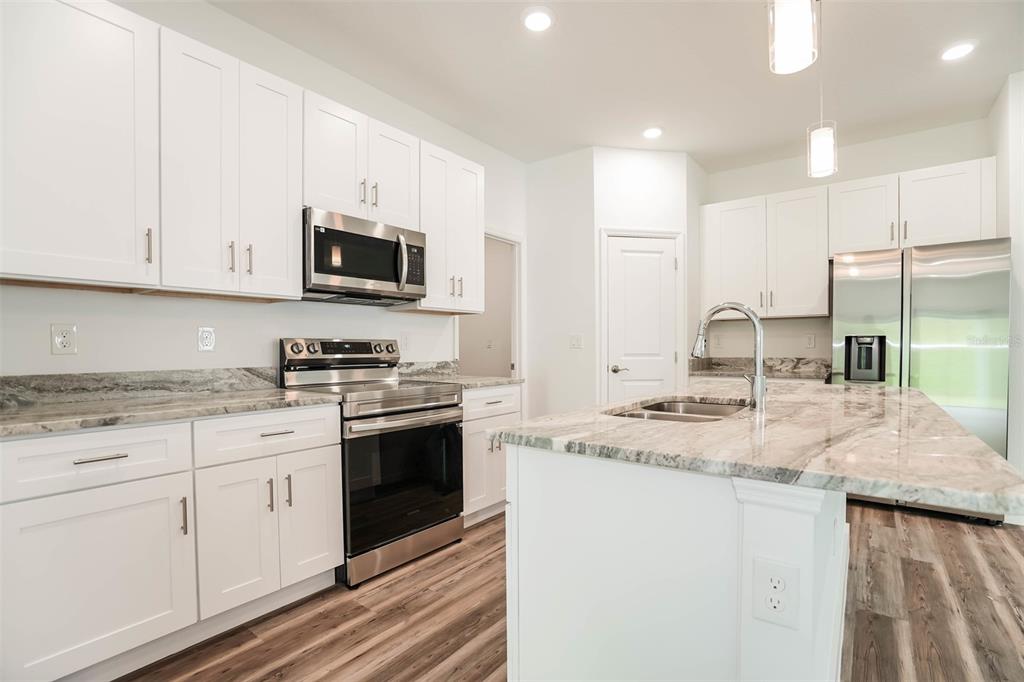 A modern kitchen features white cabinets, stainless steel appliances, and a marble-patterned island countertop — 4475 NW 1ST TERRACE, OCALA, FL