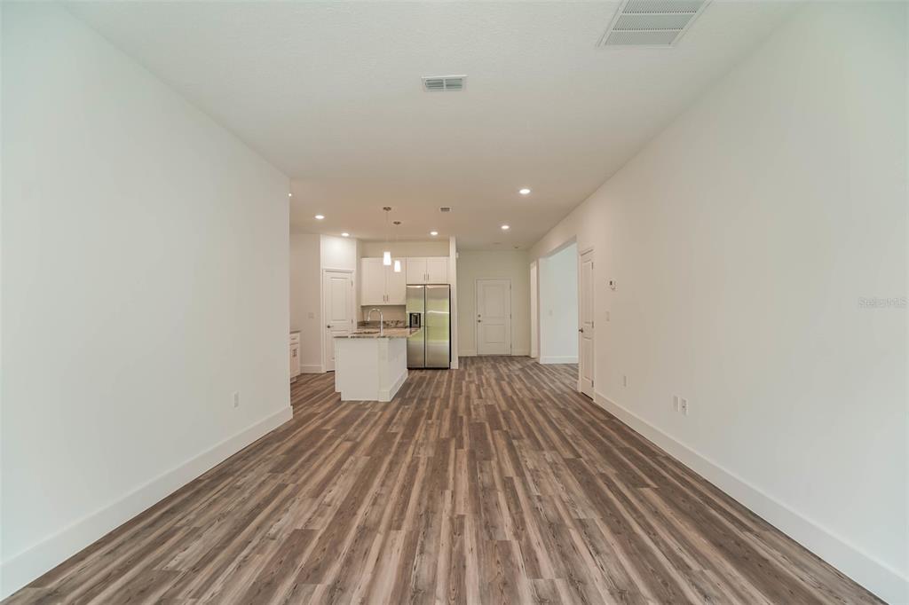 An open-concept living area features light wood-look flooring and a kitchen with white cabinetry — 4475 NW 1ST TERRACE, OCALA, FL