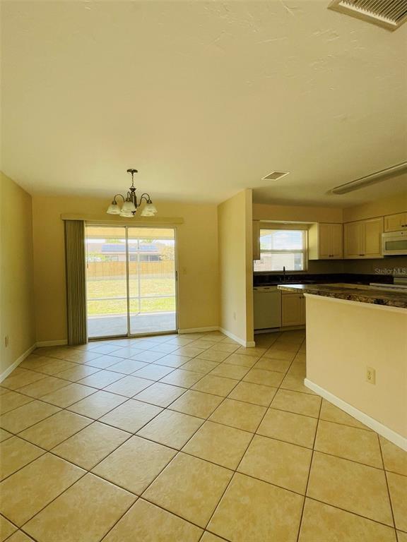 A dining area with tile flooring, a chandelier, and sliding glass doors leading to a yard — 1506 DEWITT STREET, PORT CHARLOTTE, FL