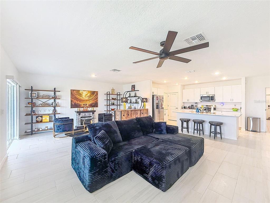 A spacious open-concept living room and kitchen featuring a large dark sectional sofa — 12227 RADIANT GEM TRAIL, PARRISH, FL