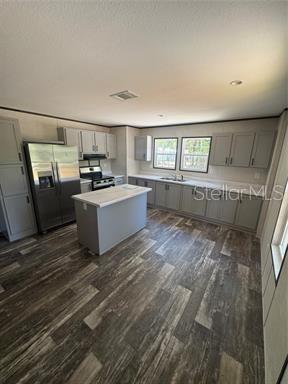 A kitchen features grey cabinets, stainless steel appliances, a center island, and wood-look flooring — 8630 SW 82ND TERRACE, TRENTON, FL