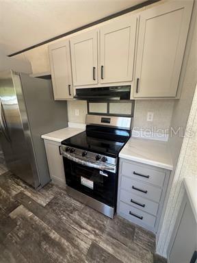 A kitchen features light gray cabinets, stainless steel appliances, and wood-look flooring — 8630 SW 82ND TERRACE, TRENTON, FL