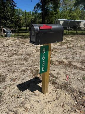 A black mailbox sits on a wooden post with a green address sign attached — 8630 SW 82ND TERRACE, TRENTON, FL