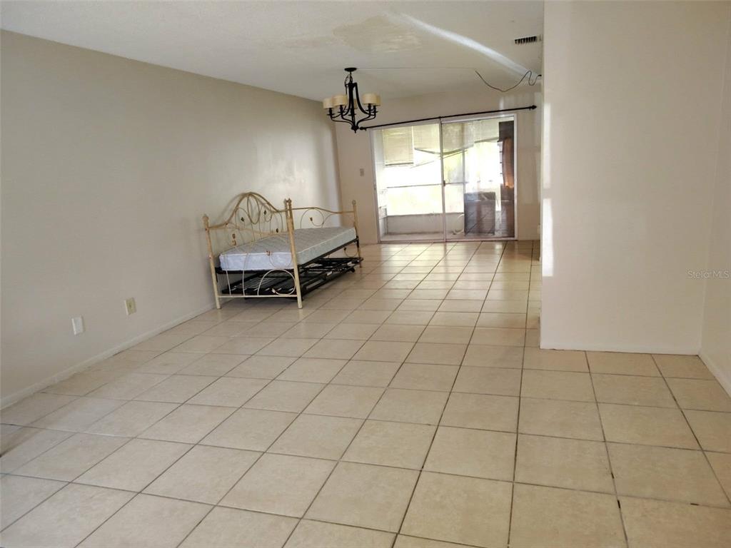 A living room with beige walls, tile flooring, a daybed, and a sliding glass door — 3715 COLBY STREET, SARASOTA, FL