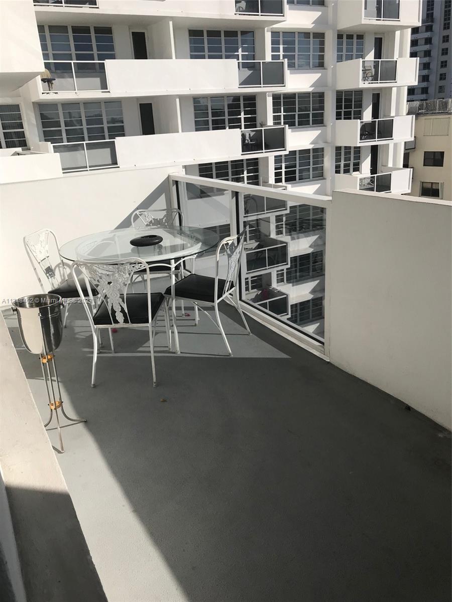 A balcony features a glass-topped table with four chairs and a metal ice bucket stand — 100 Lincoln Rd # 1007, Miami Beach FL 33139, MIAMI BEACH, FL