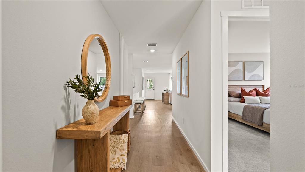 A hallway with a wooden console table and mirror leads toward a bedroom and kitchen — 6103 SWAMP BAY DRIVE, EDGEWATER, FL