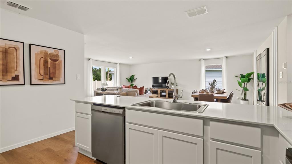 A kitchen island with a stainless steel dishwasher and sink overlooks an open-concept living area — 6103 SWAMP BAY DRIVE, EDGEWATER, FL