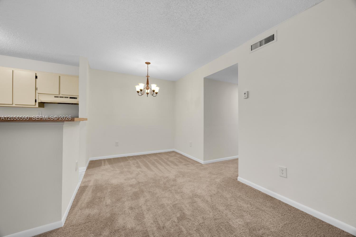 A dining area features beige carpeting, light-colored walls, and a hanging chandelier — 9711 Hammocks Blvd # K, Miami FL 33196, MIAMI, FL